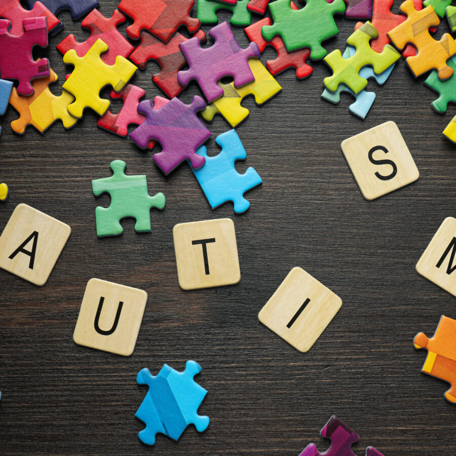 Multicolored puzzle pieces with the word "autism" on a black background. World autism day concept